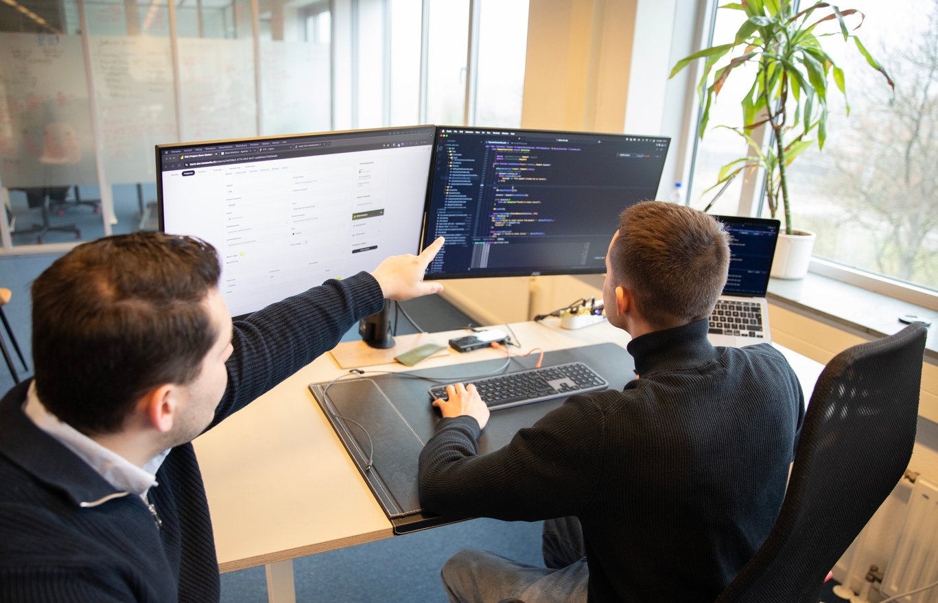 Man aan het programmeren terwijl collega meekijkt